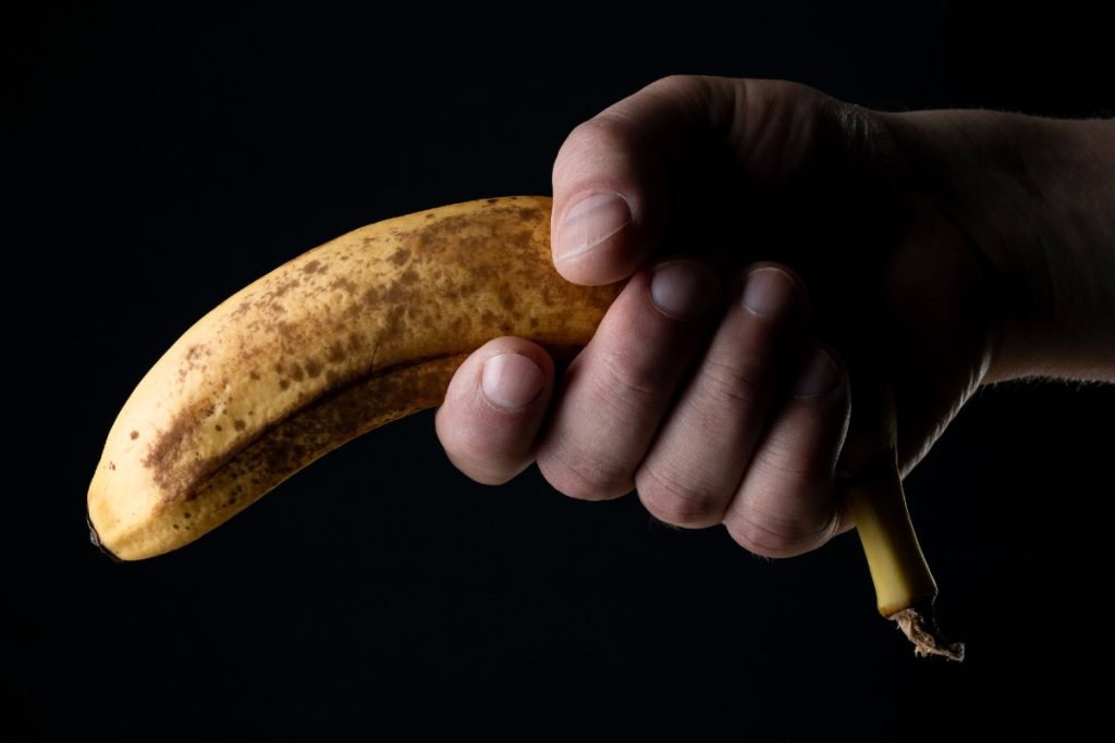 Eine Hand, die eine nach unten gerichtete Banane hält