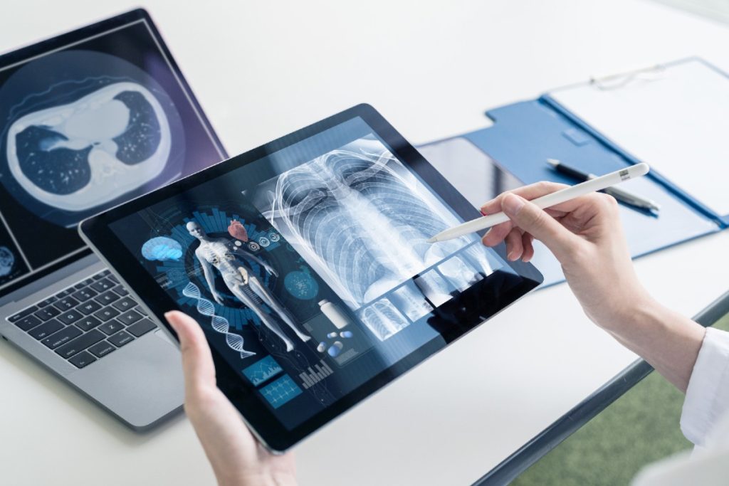Ärztin, die Röntgenbilder und Bodyscnas am Tablet überprüft