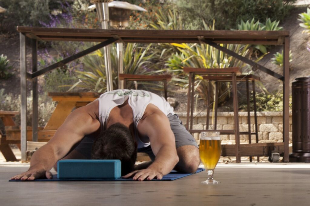 Mann bei einer Yoga-Übung mit einem Bier vor sich