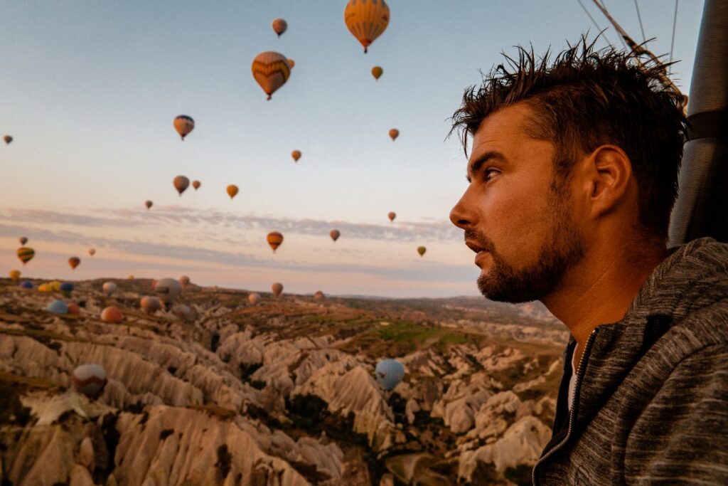 Mann seitlich, hoch oben in Heißluftballon, mit anderen Ballons im Hintergrund