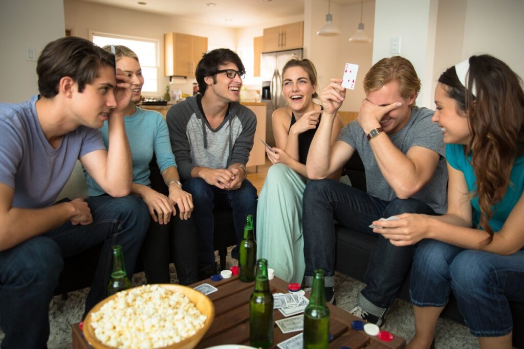 Gruppe junger Menschen auf Sofas bei einem Gesellschaftsspiel mit Karten