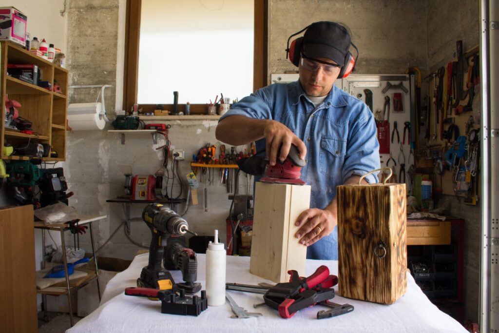 Mann mit Gehörschutz in Werkstatt, der an einem Holzblock arbeitet
