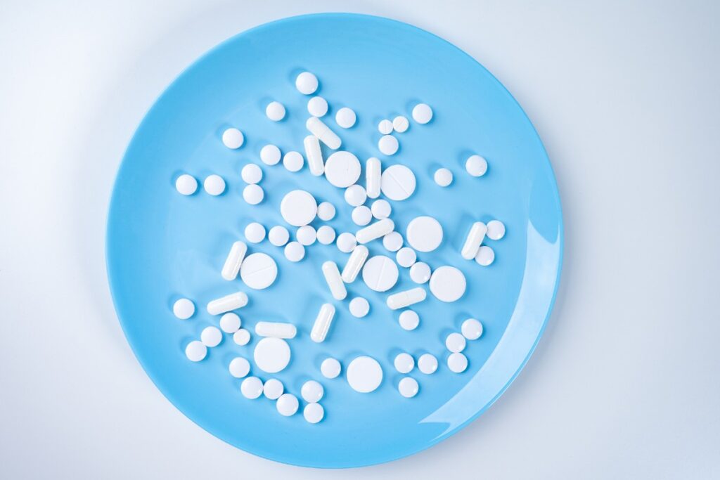 Weiße Pillen verschiedener Form auf einem blauen Teller
