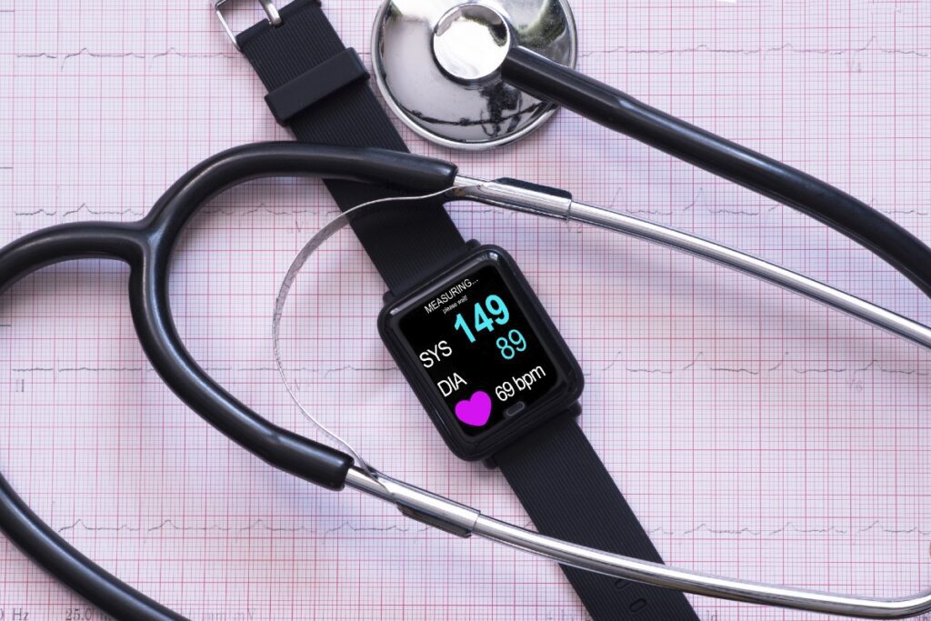 Fitnessuhr und Stethoskop auf einem Millimeterpapier mit Herzfrequenz