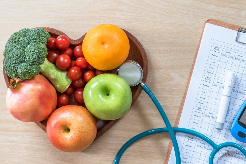 Eine Schale Obst und Gemüse neben medizinischem Klemmbrett und Stethoskop