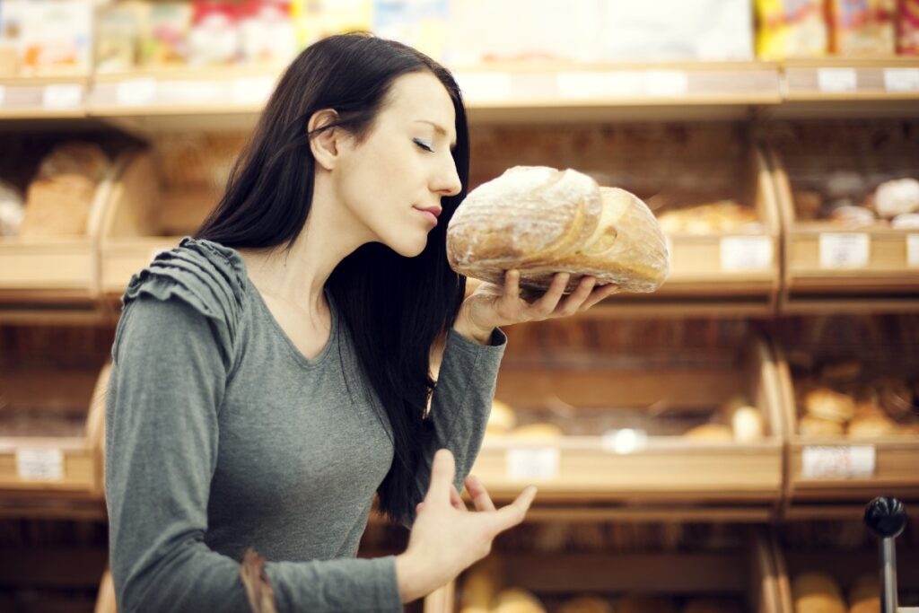 Junge Frau, die genussvoll an einem frischen Brot riecht
