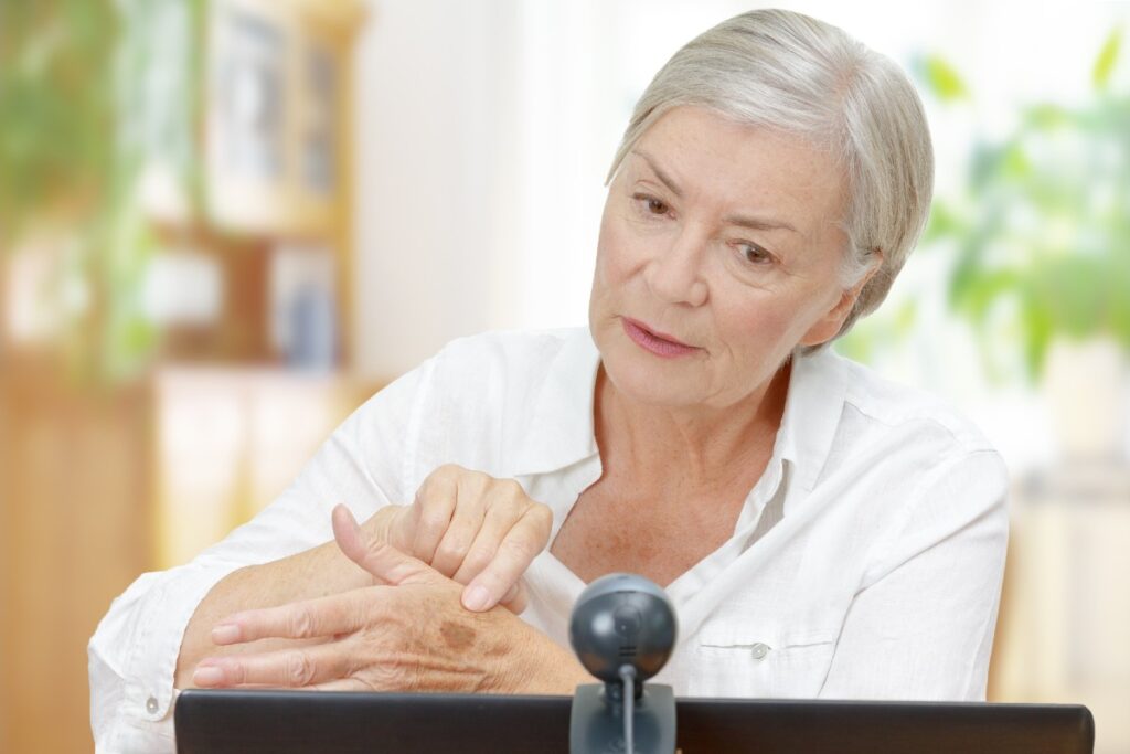 Ältere Frau vor Laptop im Gespräch mit Arzt
