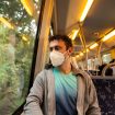 Junger Mann mit Maske in öffentlichem Verkehrsmittel