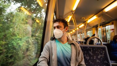 Junger Mann mit Maske in öffentlichem Verkehrsmittel