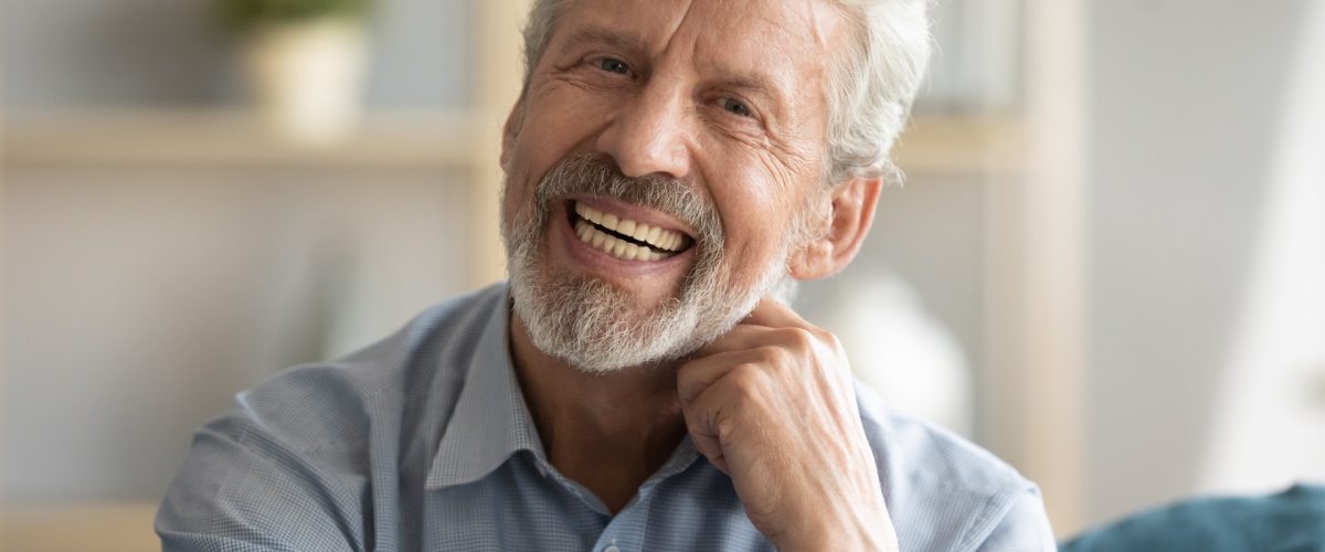 Älterer Mann, der lachend in die Kamera schaut