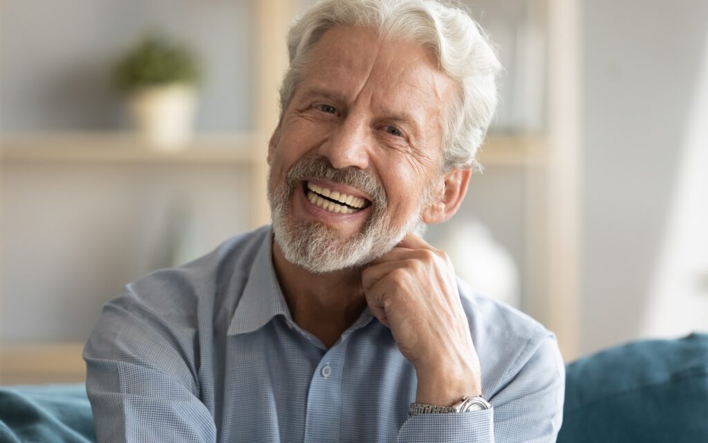 Älterer Mann, der lachend in die Kamera schaut