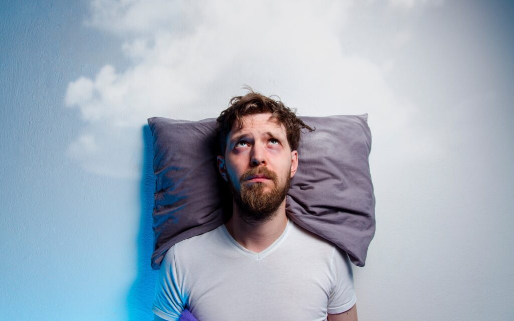 Schlafloser Mann mit Kopf auf Kissen
