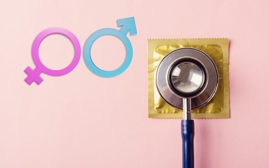 Die Zeichen für Männlichkeit und Weiblichkeit neben einem Kondom mit Stethoskop