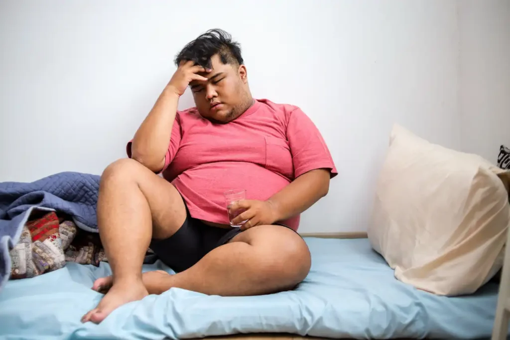 Depressiver dicker junger Mann auf Bett