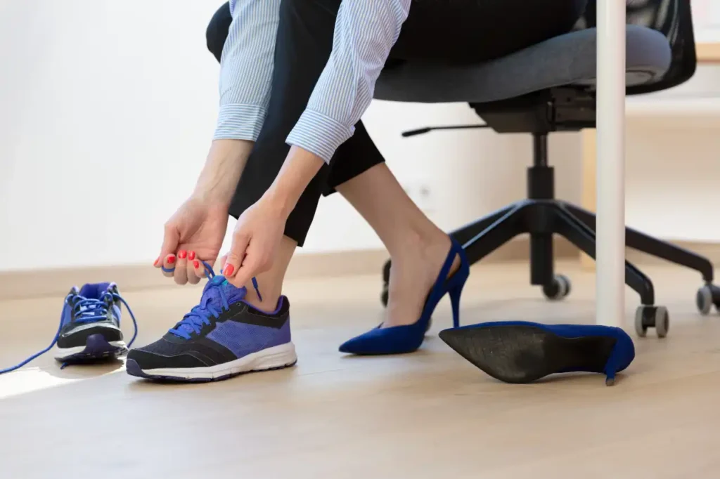 Frau zieht im Büro Sportschuhe an