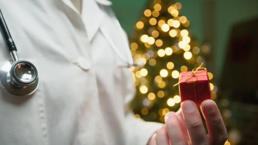 Image Arzt mit Päckchen vor Weihnachtsbaum
