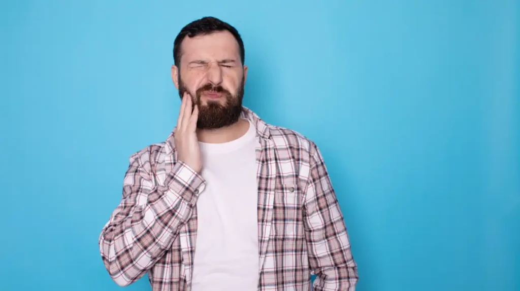 Mann hält sich schmerzende Wange