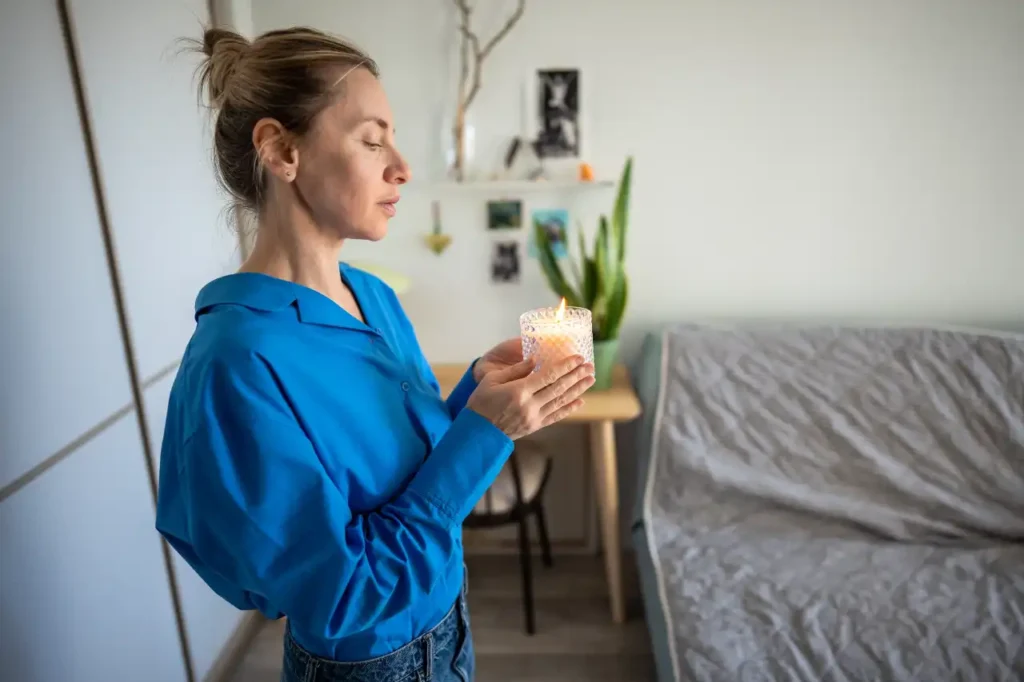 Frau mit Duftkertze im Wohnzimmer