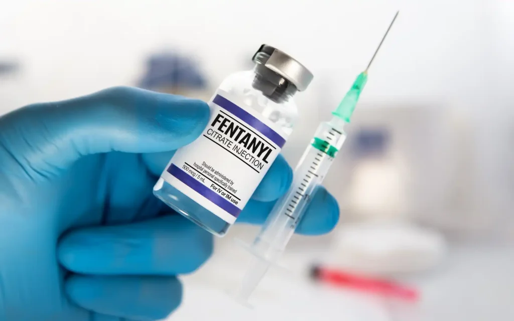 Ampulle mit Fentanyl und Spritze in einer Hand