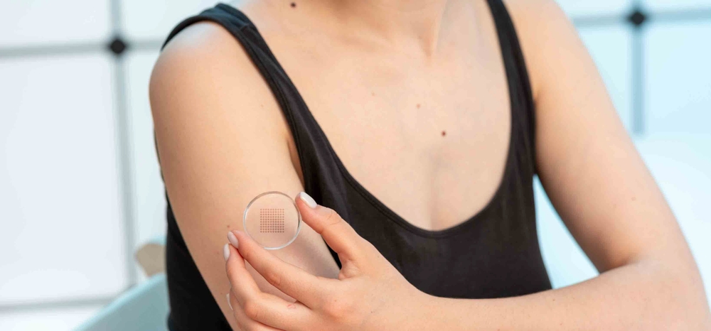 Jeune femme appliquant un patch contraceptif microneedle transdermique en gel sur son bras.