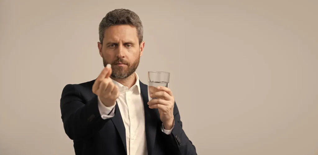 Mann hält Schmerzmittel in den Fingern