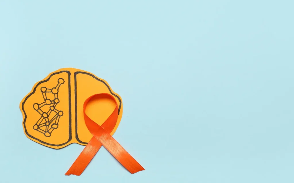 Gehirn aus Papier mot orangenfarbener Schleife erinnern an Multiple Sklerose Awareness