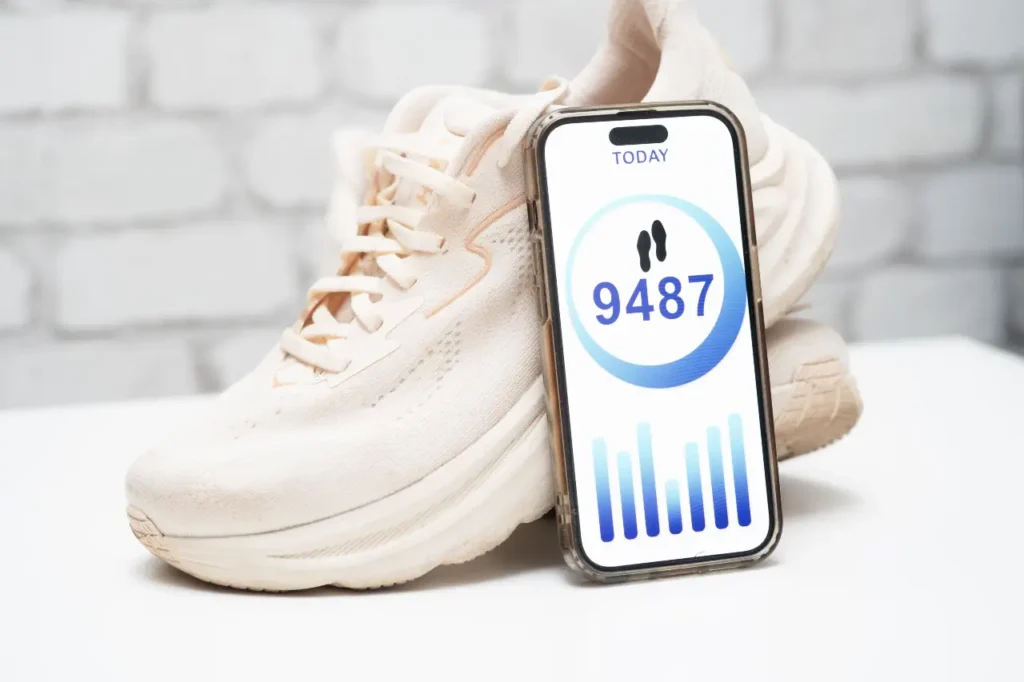 Schrittzähler auf dem Handy neben Sneaker