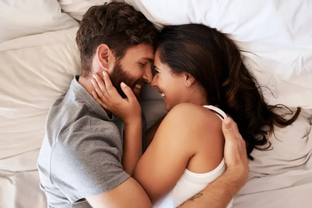 Ein Pärchen kuschelt glücklich im Bett miteinander