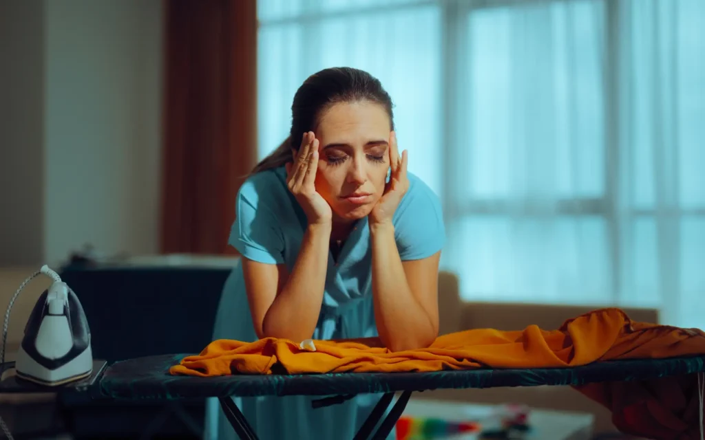 Junge Frau ist zu müde um Wäsche zu bügeln