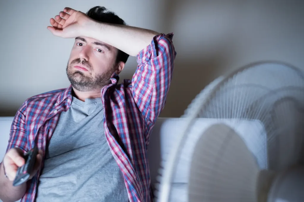 Mann schwitzt auf Couch vor dem TV
