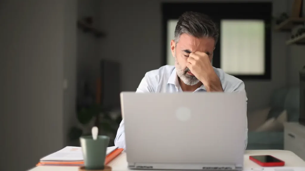 Mann erschöpft vor Laptop