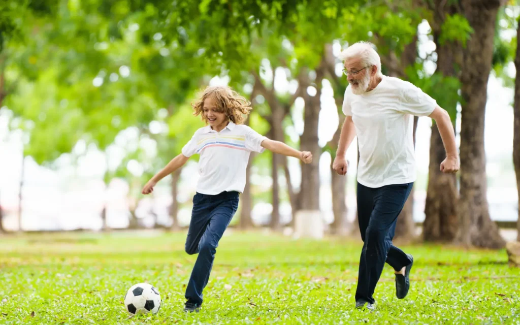Opa spielt mit Enkel im Park Fussball