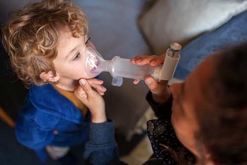 Parent aidant son enfant asthmatique avec un inhalateur