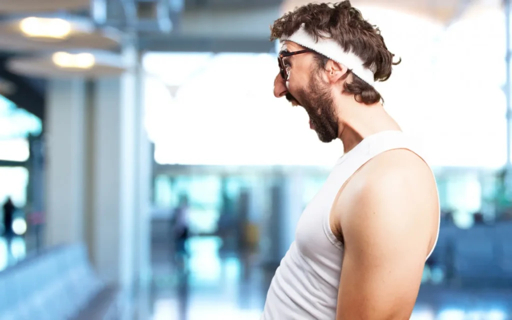 Witziger Mann mit Stirnband und Brille im Fitnessstudio