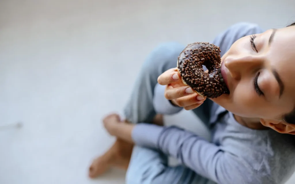 Junge Frau isst Donut mit Genuss
