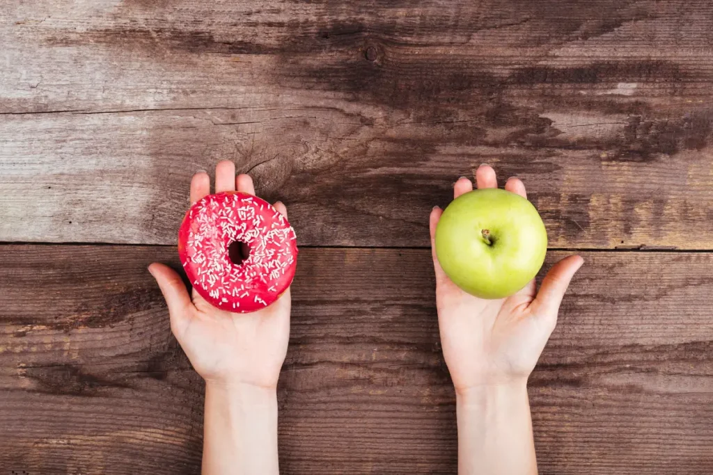 Hände mit Apfel und Donut
