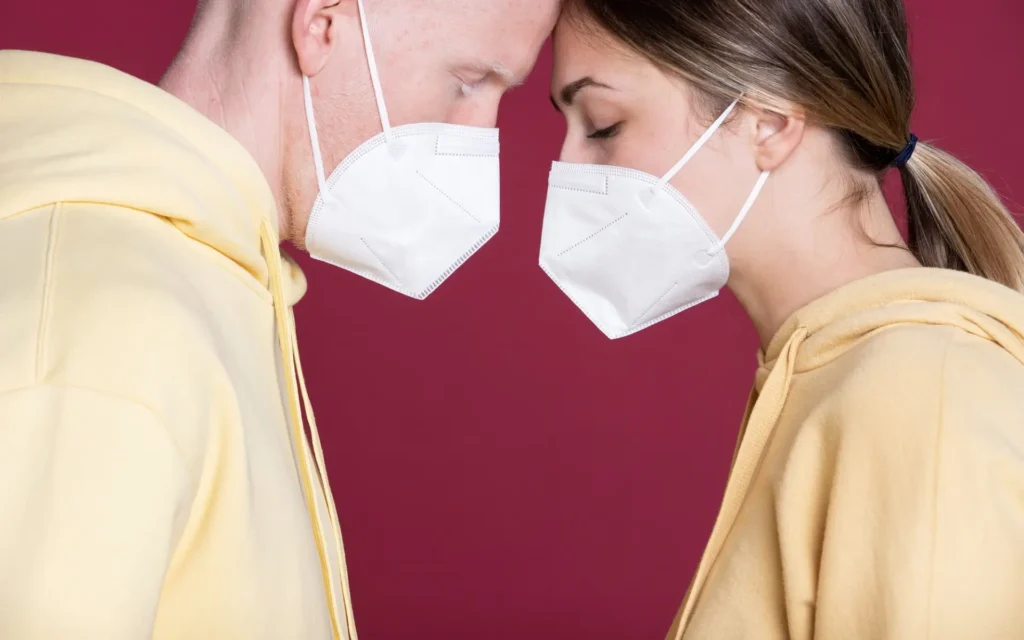 Mann und Frau stehen sich mit Masken auf gegenüber