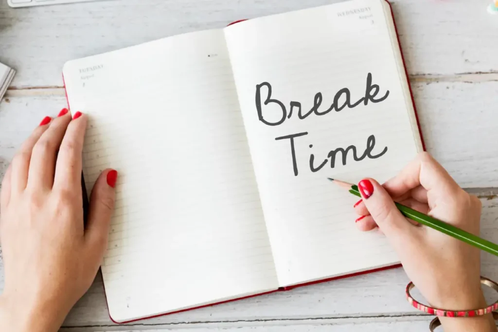 Aufgeschlagenes Notizbuch mit den Worten BREAK TIME und einer Frauenhand