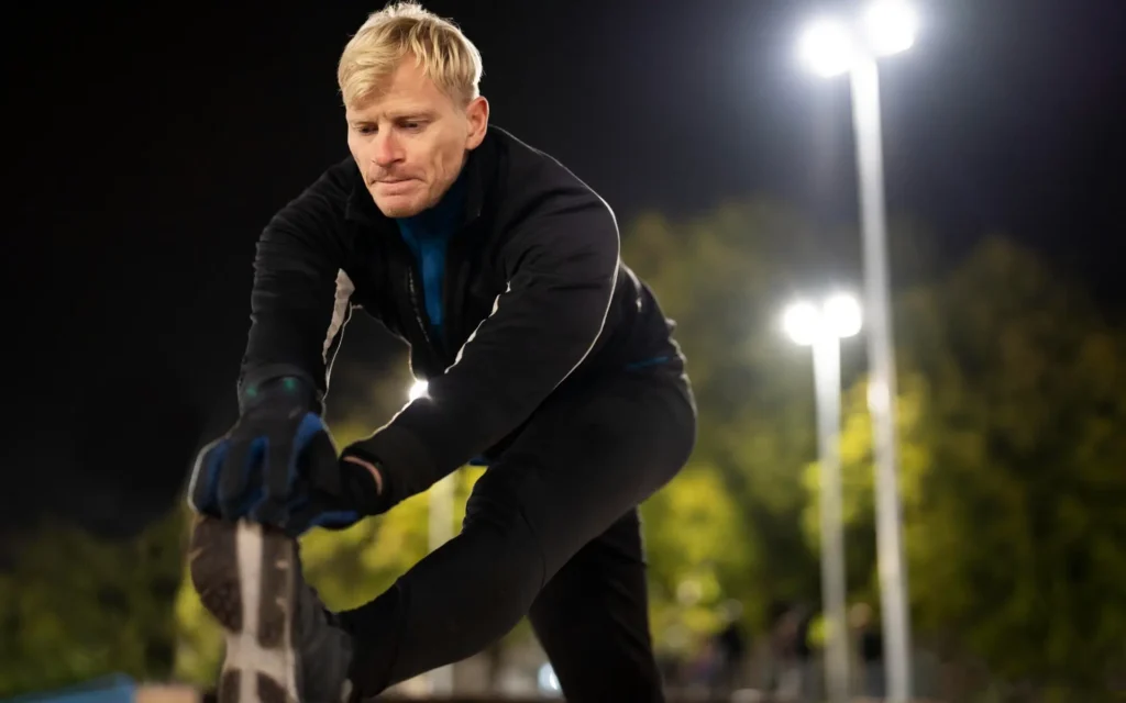 Mann stretcht abends vor dem Jogging