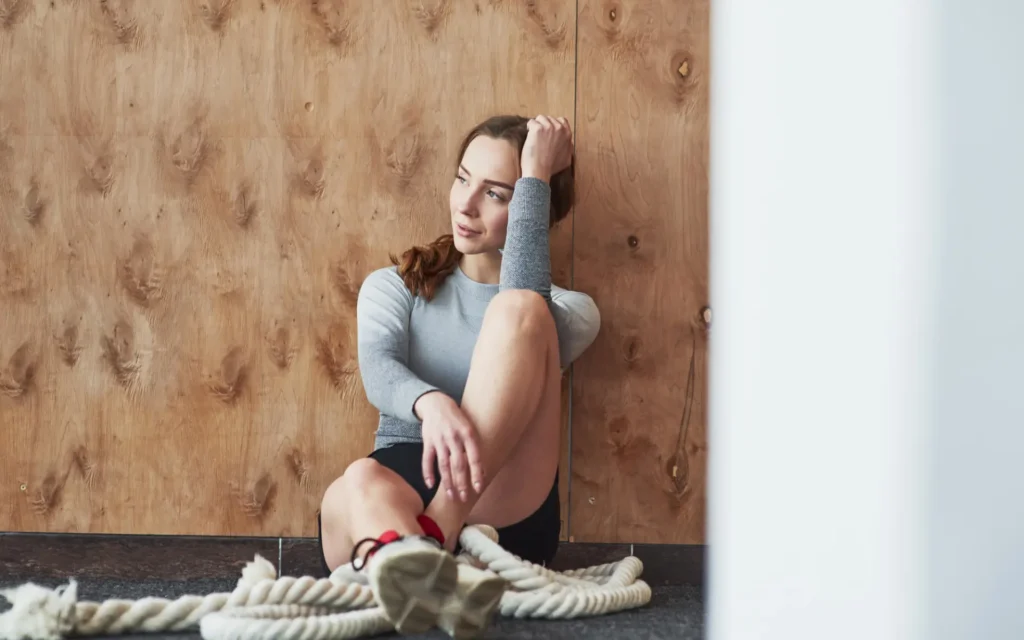 An die Holzwand gelehnt. Sportliche junge Frau beim Fitnesstag im Fitnessstudio