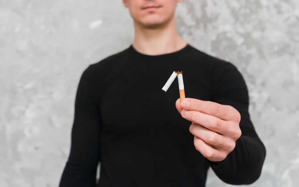 Mann hält zerbrochene Zigarette in der Hand