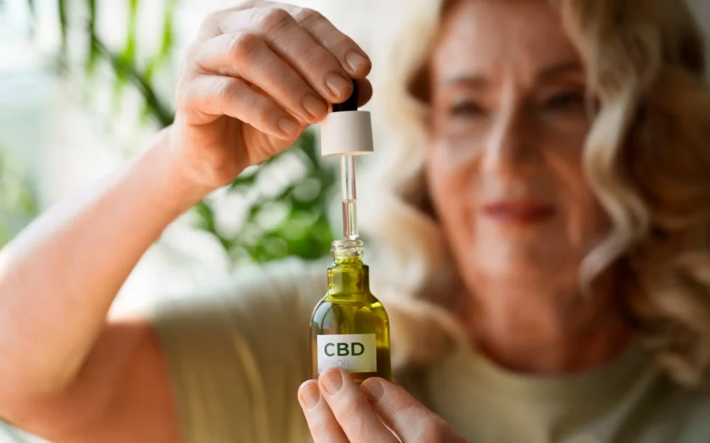 Frau hält eine Flasche CBD-Öl und zieht mit einer Pipette Öl daraus auf.