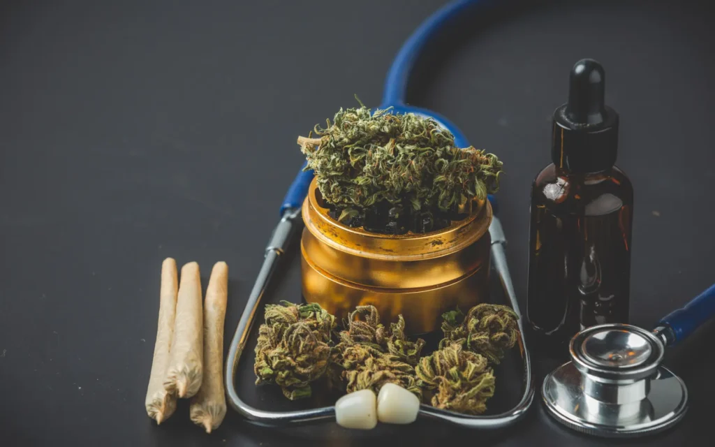 Cannabisblüten und Cannabisöl liegen zusammen mit einem Stethoskop auf einer dunklen Oberfläche.