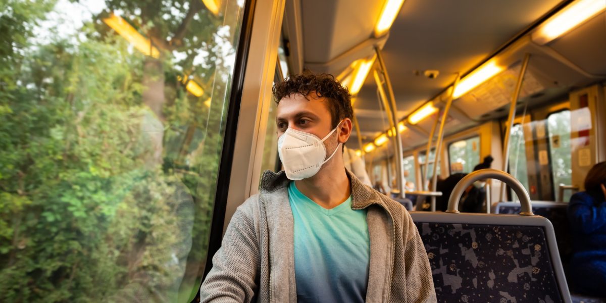 Junger Mann mit Maske in öffentlichem Verkehrsmittel