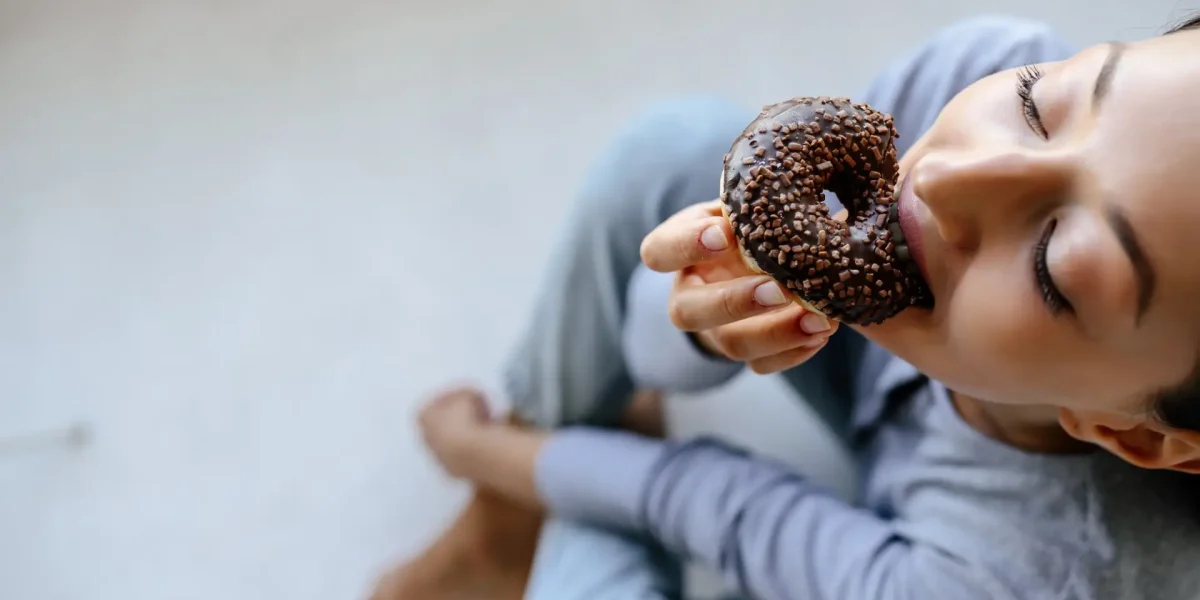 Junge Frau isst Donut mit Genuss