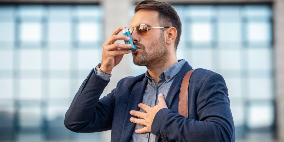 Junger Geschäftsmann, mit Sonnenbrille und Inhaler