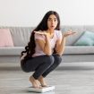 Überraschte junge Frau auf Waage