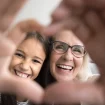 Oma und Enkelin machen lächelnd das Herzzeichen mit den Händen