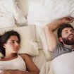 Paar im Bett und Frau kann wegen seinem Schnarchen nicht schlafen