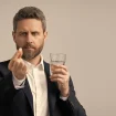 Mann hält Schmerzmittel in den Fingern